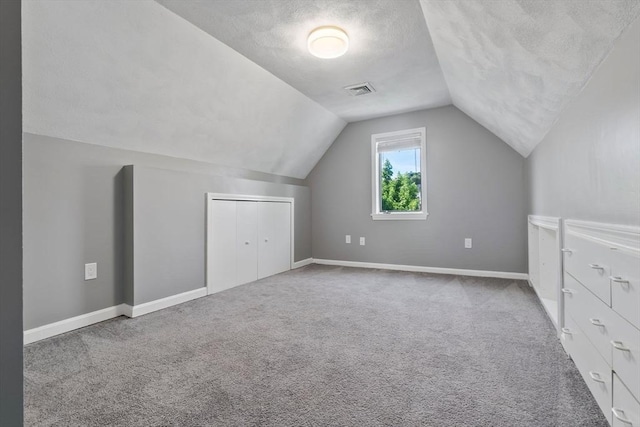 bonus room with vaulted ceiling, a textured ceiling, carpet floors, and baseboards