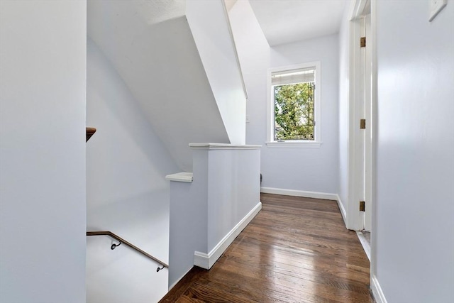 hallway with an upstairs landing, wood finished floors, and baseboards
