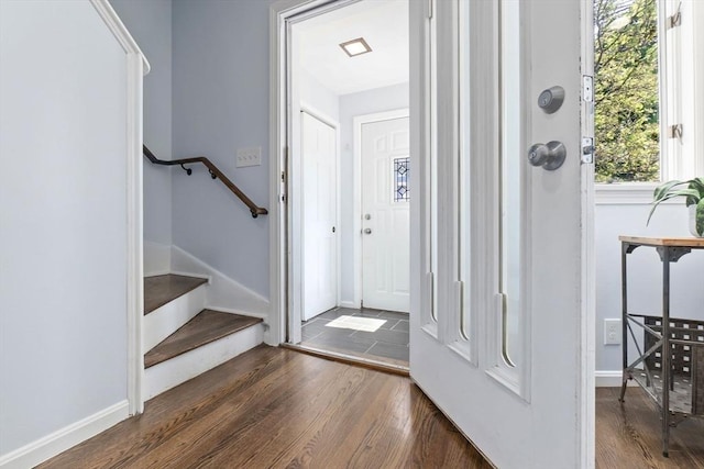 foyer entrance featuring dark wood-type flooring, stairway, and baseboards