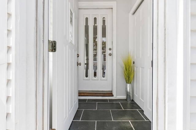 doorway to outside with dark tile patterned flooring and baseboards
