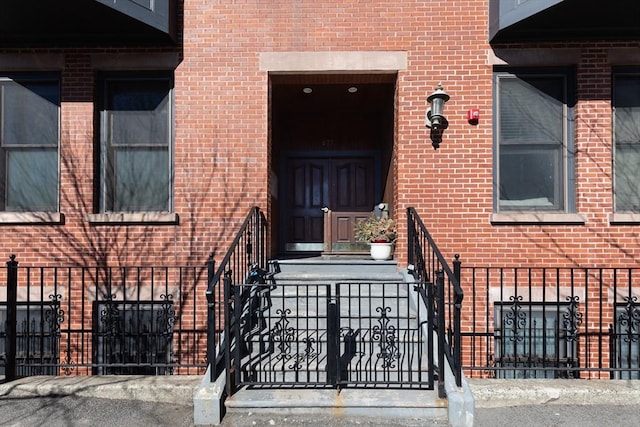 property entrance featuring brick siding and fence