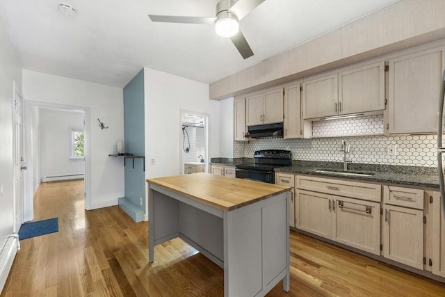 281 Chelsea St Unit 2A, Boston, MA 02128 - kitchen with black electric range, under cabinet range hood, butcher block counters, a baseboard heating unit, and backsplash