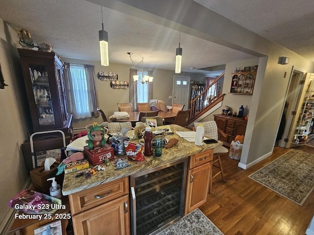 kitchen with light stone counters, wine cooler, decorative light fixtures, and brown cabinets