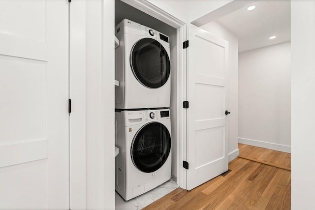 clothes washing area with light hardwood / wood-style floors and stacked washer / dryer