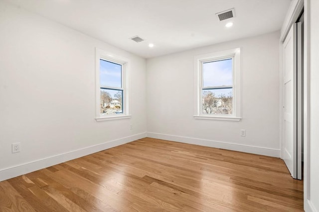 unfurnished bedroom featuring multiple windows, light hardwood / wood-style floors, and a closet