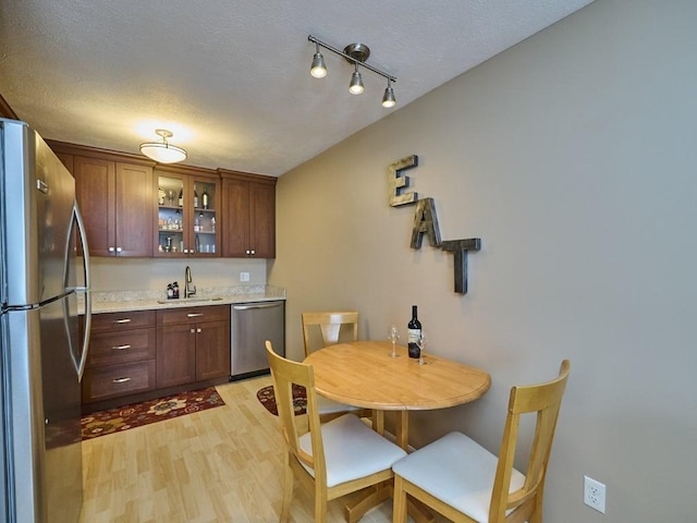71 Princeton St Unit 305, Chelmsford, MA 01863 - kitchen featuring appliances with stainless steel finishes, a sink, light countertops, light wood-type flooring, and glass insert cabinets