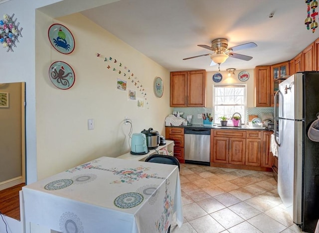 kitchen with appliances with stainless steel finishes, sink, light tile patterned flooring, ceiling fan, and decorative backsplash