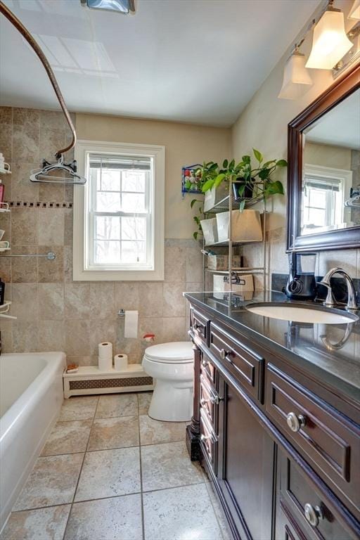 full bathroom with tile walls, vanity, tiled shower / bath, toilet, and tile patterned floors