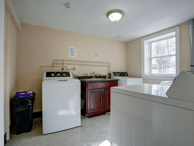 clothes washing area featuring sink, cabinets, and separate washer and dryer