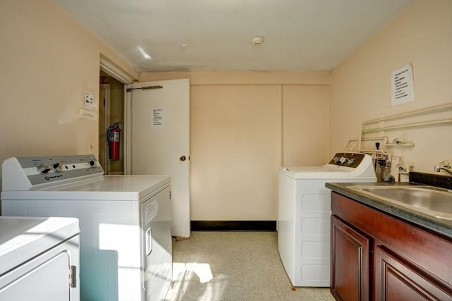 washroom with cabinets, washing machine and dryer, and sink