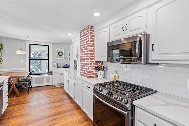 kitchen featuring light stone counters, stainless steel appliances, white cabinets, light wood-type flooring, and decorative light fixtures