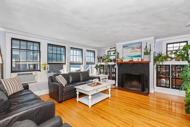 living room featuring ornamental molding, a brick fireplace, baseboards, and wood finished floors