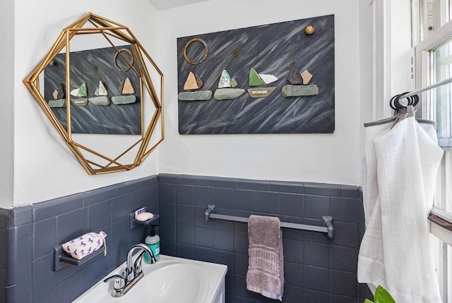 bathroom with wainscoting, a sink, and tile walls