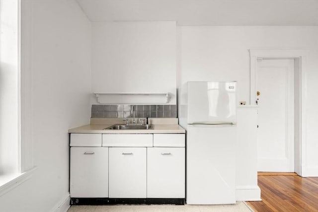 97 Chester St Unit 8, Boston, MA 02134 - kitchen featuring freestanding refrigerator, light countertops, white cabinetry, decorative backsplash, and light wood-style flooring
