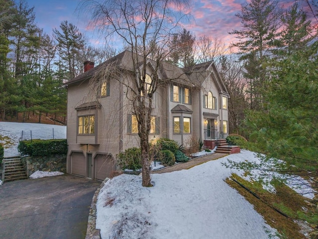 view of front of property featuring aphalt driveway, a chimney, and an attached garage