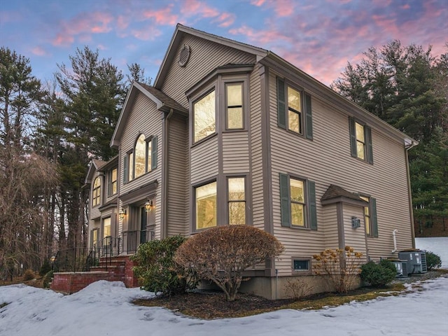 snow covered property with central air condition unit