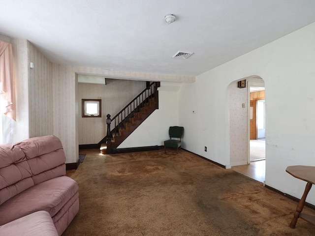 living room with visible vents, arched walkways, baseboards, carpet flooring, and wallpapered walls