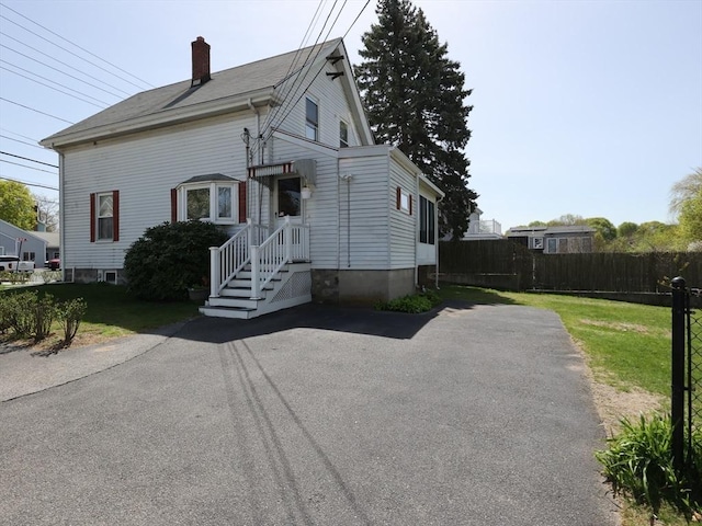 view of front of home featuring fence, a chimney, and a front lawn