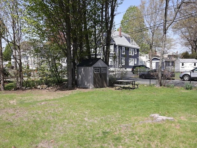 view of yard featuring an outdoor structure, fence, and a storage shed
