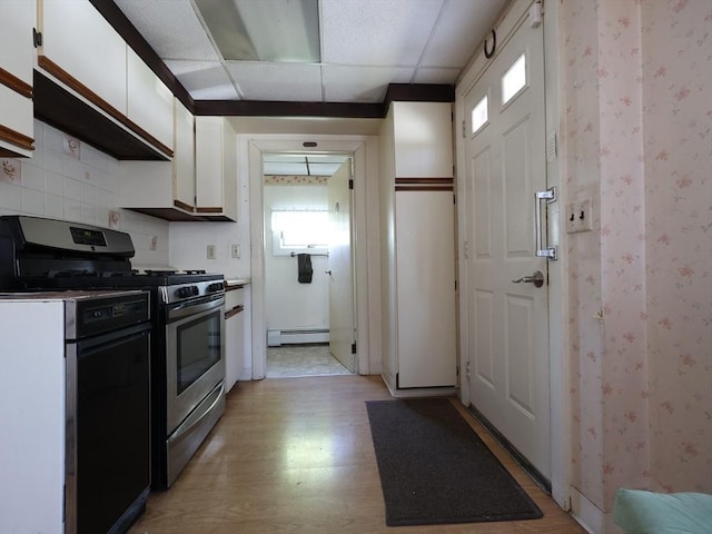kitchen with stainless steel gas stove, light wood-type flooring, plenty of natural light, white cabinets, and a baseboard radiator