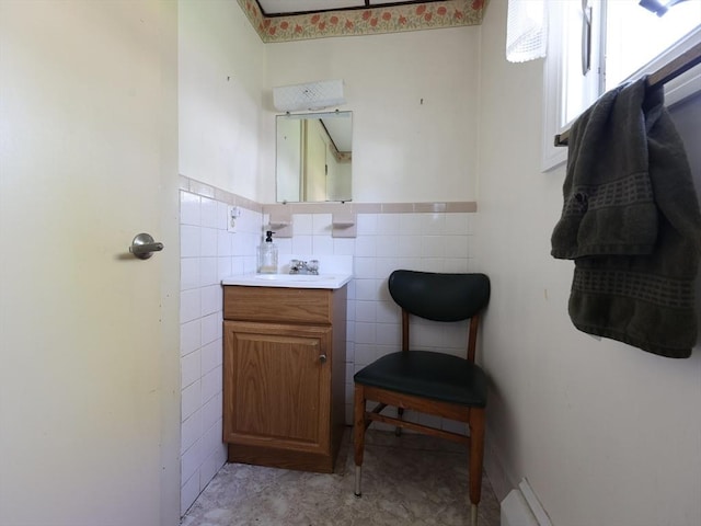 half bathroom with vanity, wainscoting, and tile walls