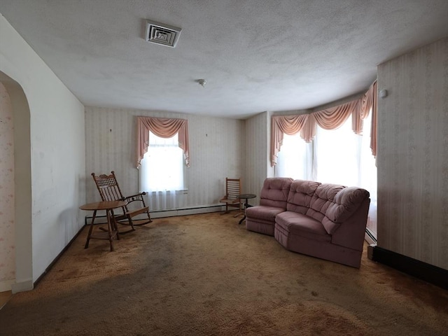 carpeted living room with a textured ceiling, visible vents, arched walkways, a baseboard heating unit, and wallpapered walls