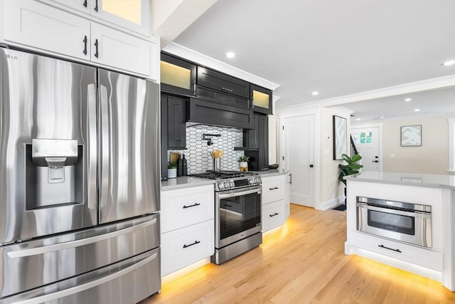 586 Lowell St, Peabody, MA 01960 - kitchen featuring appliances with stainless steel finishes, light countertops, decorative backsplash, light wood finished floors, and glass insert cabinets