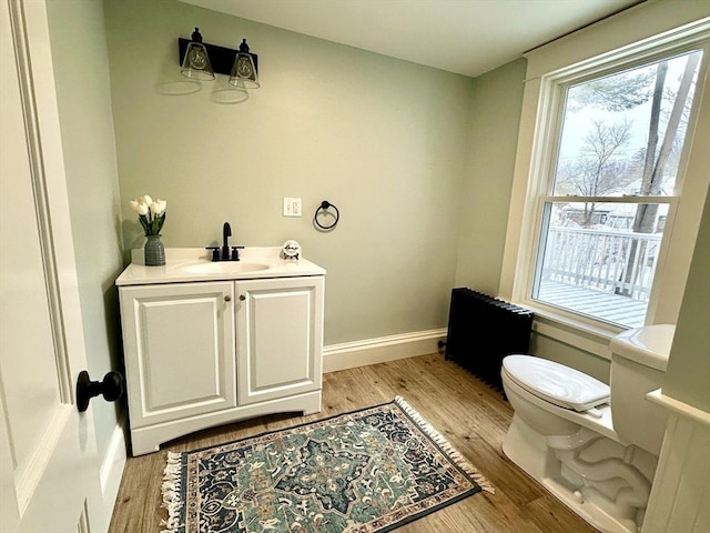 bathroom with baseboards, vanity, toilet, and wood finished floors