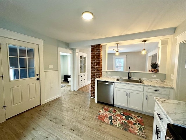 kitchen featuring light wood-style floors, wainscoting, a sink, white cabinetry, and dishwasher