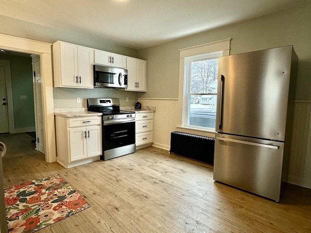 kitchen featuring stainless steel appliances, radiator heating unit, and light wood-style flooring