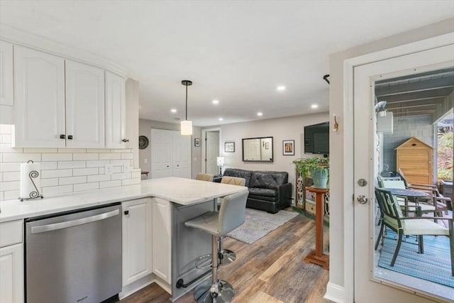 kitchen with hanging light fixtures, white cabinetry, stainless steel dishwasher, and dark hardwood / wood-style floors