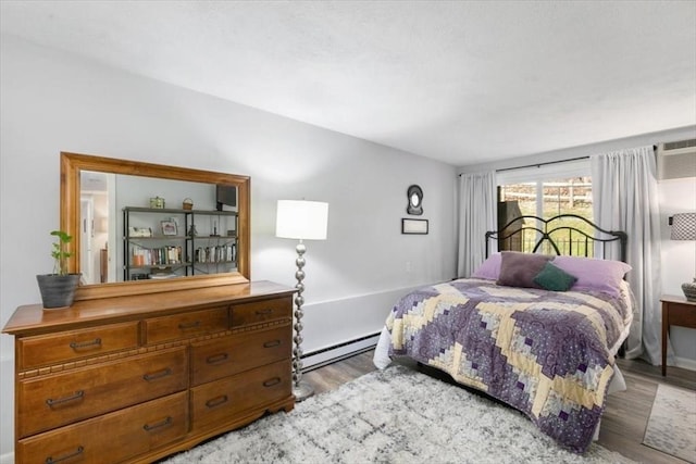 bedroom with a baseboard radiator, light hardwood / wood-style flooring, and a wall unit AC