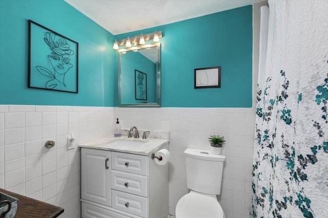 bathroom featuring vanity, toilet, tile walls, and walk in shower