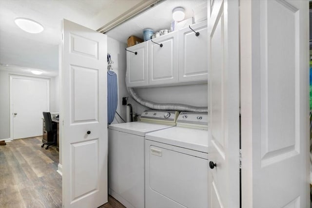 laundry area featuring cabinets, wood-type flooring, and washing machine and dryer