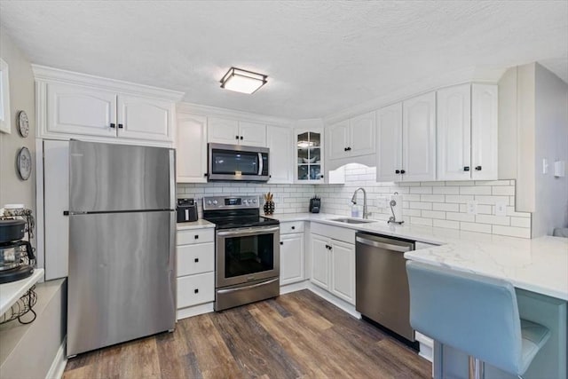 kitchen with dark wood-type flooring, sink, light stone countertops, appliances with stainless steel finishes, and white cabinetry