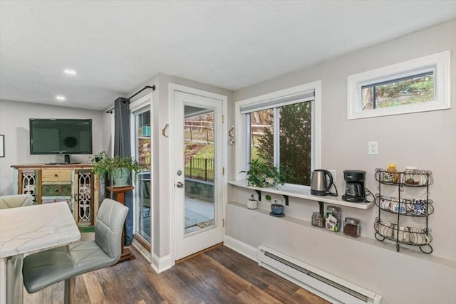 doorway featuring dark wood-type flooring, a wealth of natural light, and a baseboard heating unit