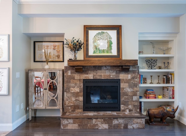 living room with built in features, a fireplace, dark hardwood / wood-style floors, and ornamental molding