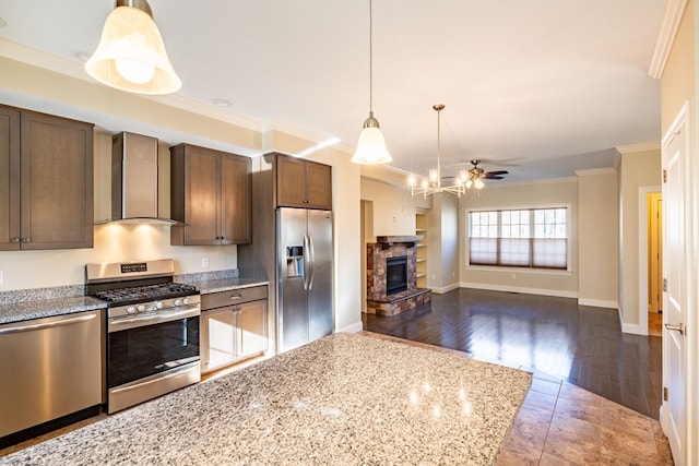 kitchen with wall chimney exhaust hood, light stone countertops, a fireplace, dark hardwood / wood-style flooring, and stainless steel appliances