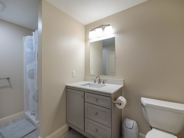 bathroom featuring a textured ceiling, vanity, toilet, and walk in shower