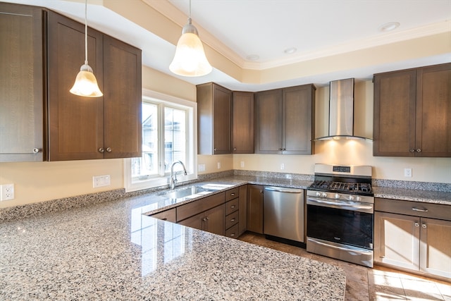 kitchen with light stone countertops, wall chimney exhaust hood, stainless steel appliances, sink, and decorative light fixtures