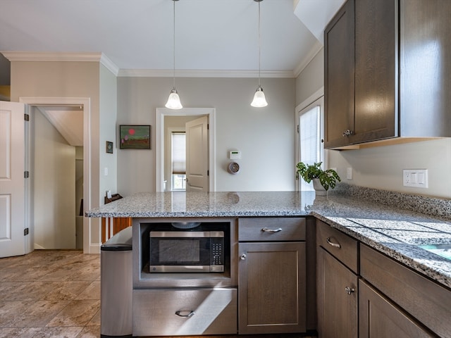 kitchen featuring dark brown cabinetry, light stone countertops, kitchen peninsula, decorative light fixtures, and ornamental molding