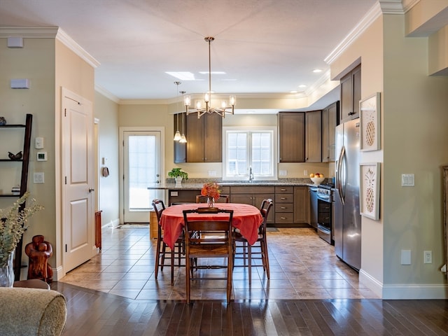 kitchen with crown molding, wood-type flooring, hanging light fixtures, and appliances with stainless steel finishes