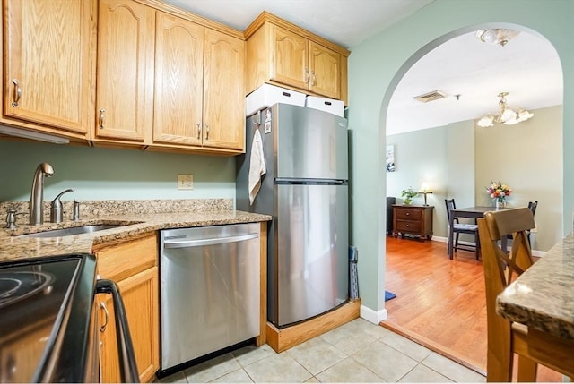 230 Willard St Unit 412, Quincy, MA 02169 - kitchen featuring stainless steel appliances, arched walkways, a sink, light brown cabinets, and light stone countertops