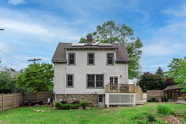 454 Webster St, Needham, MA 02494 - back of property with a chimney, a deck, roof mounted solar panels, and roof with shingles