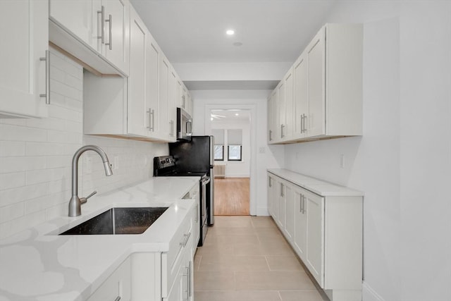 kitchen with light stone counters, appliances with stainless steel finishes, sink, and white cabinets