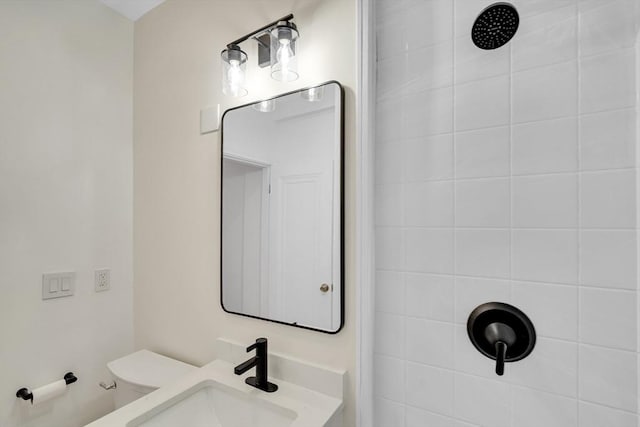 bathroom with vanity, tiled shower, and toilet