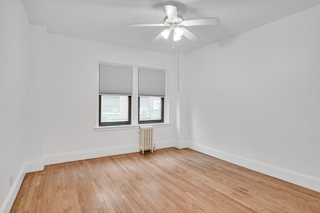 spare room featuring radiator, light hardwood / wood-style floors, and ceiling fan