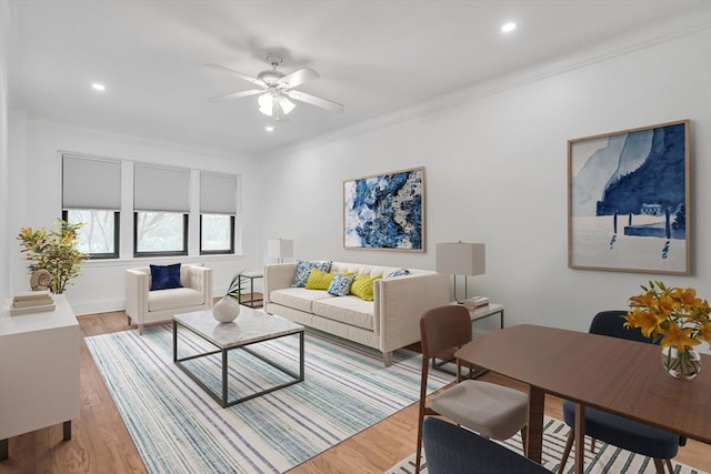 living room with crown molding, ceiling fan, and light wood-type flooring