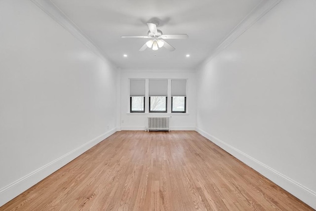 spare room with radiator heating unit, ornamental molding, ceiling fan, and light wood-type flooring