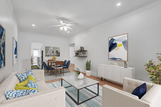 living room with crown molding, ceiling fan, and light hardwood / wood-style flooring